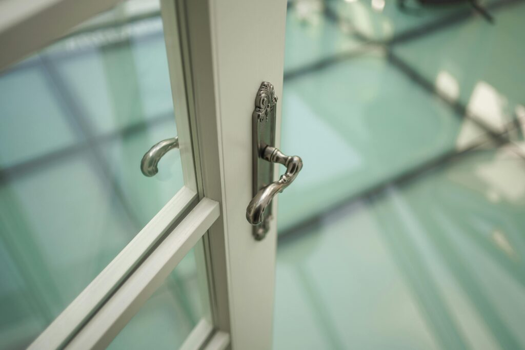 Close-up of an ornate French door handle with soft lighting and modern background