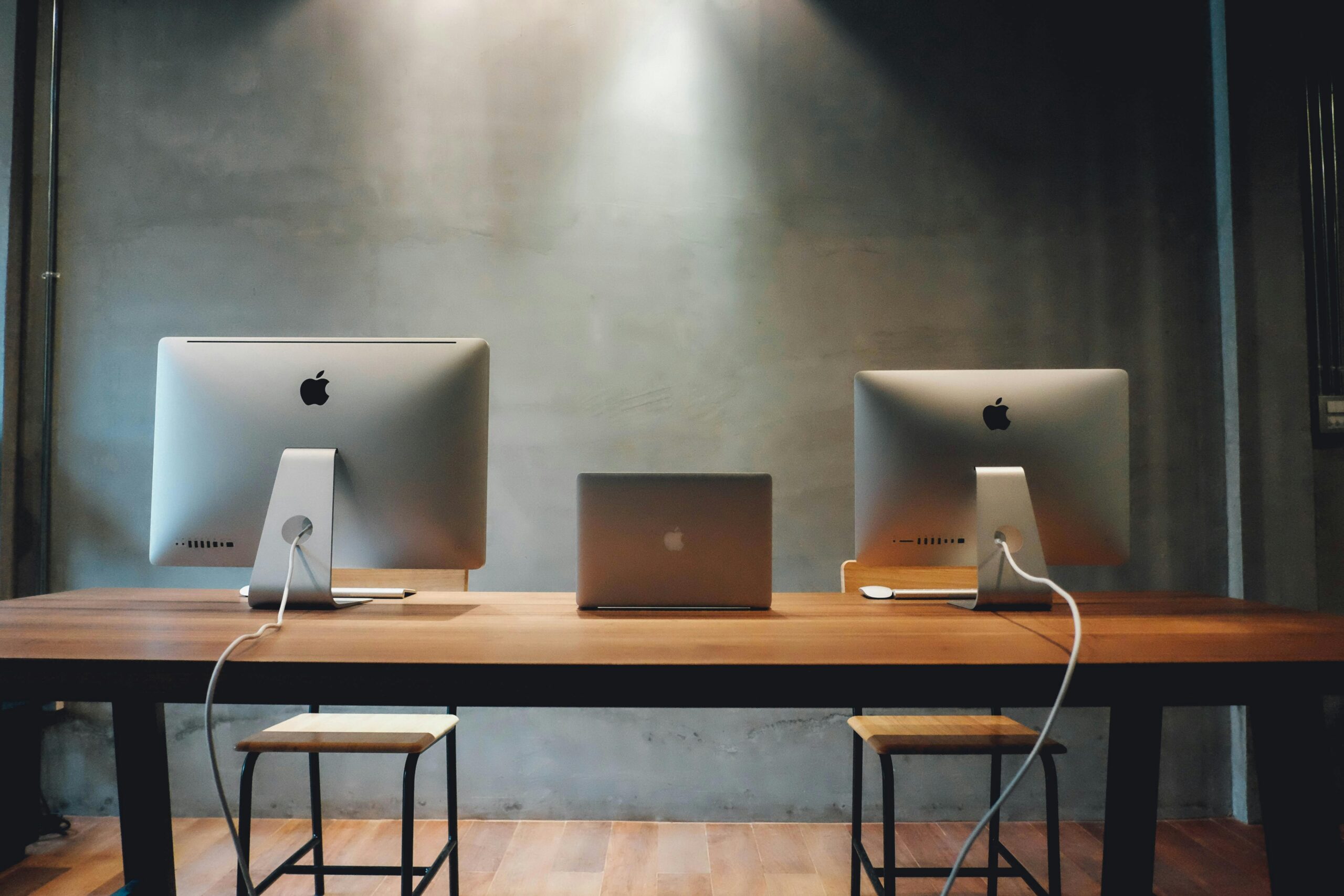 Minimalist office space with dual monitors on a wooden table, promoting a contemporary work environment.